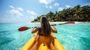 Person driving a boat near a pristine beach in the Maldives with clear blue waters and a sunny sky.