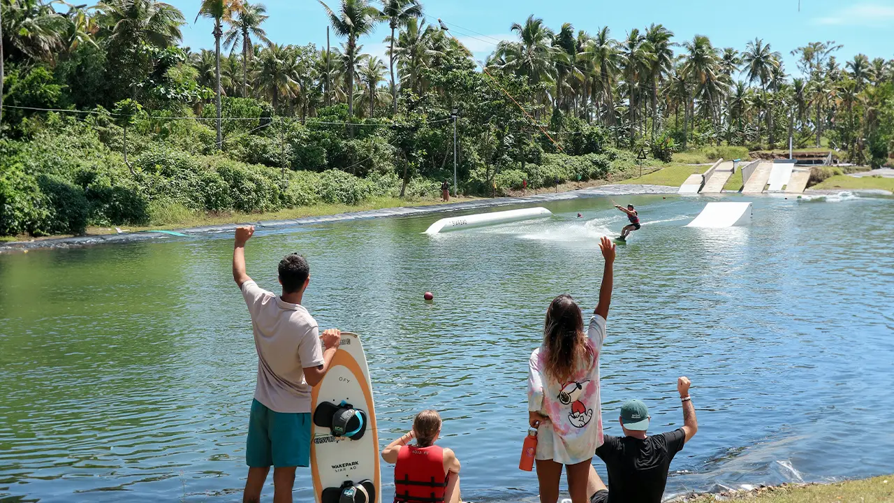 Group of people cheering their friend while she's wakeboarding on a resort in siargao island