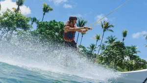 Man wakeboarding splashing the water with trees in the background in Siargao