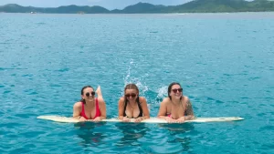 Pretty ladies having fun in the gorgeous blue waters while floating using a surf board in Siargao