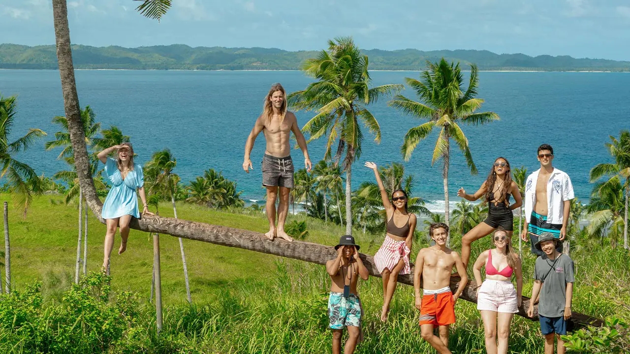 group photo of 9 people in the green fields and a background of the beautiful blue waters and mountains in siargao