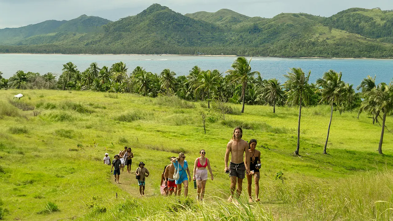 People walking trough Peaceful grasslands of Siargao