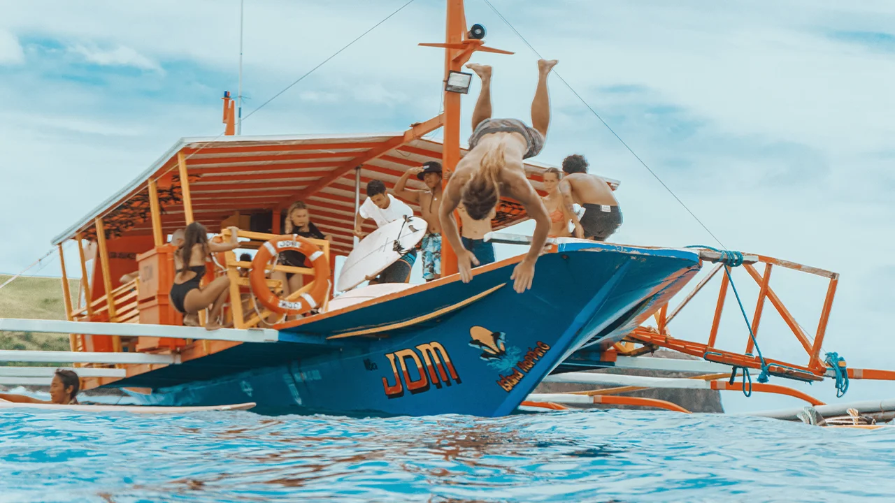 Man jumping out of the boat to dive in the blue waters of Siargao